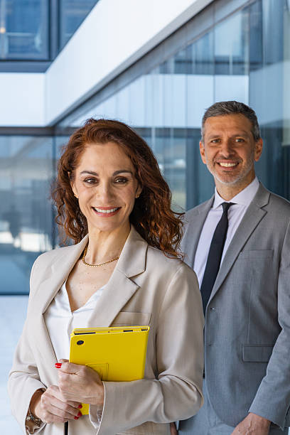 istock Business partners smiling, holding tablet, standing in modern office building, representing professionalism and collaboration 2216023075