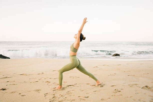 istock Young woman practicing yoga on the beach 2216023921