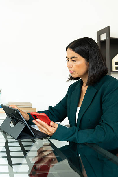 istock Professional woman working on digital devices, multitasking with tablet and smartphone at modern workspace 2216024092