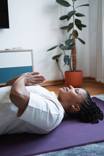 Woman Practicing Yoga While Relaxing on a Purple Mat at Home