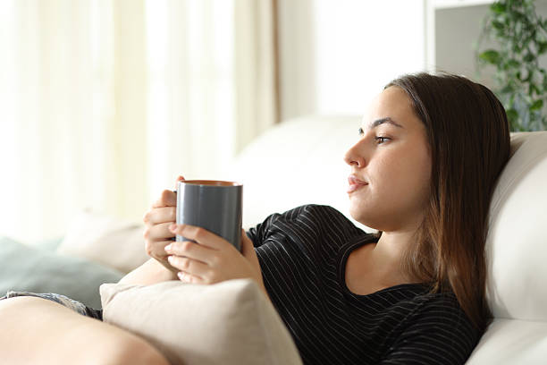 istock Abstracted woman drinking coffee looking away at home 2216025420