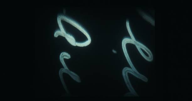 A sequence of white handwritten shapes glows on a dark screen from a 16mm projector.