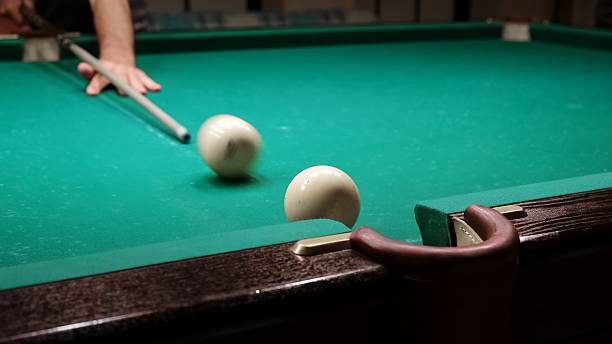 istock Playing Russian billiards on a green table. A white ball rolls and hits another which pockets into the middle pocket. A successful shot close up. Pastime at home playing sport game hobby. 2216030194