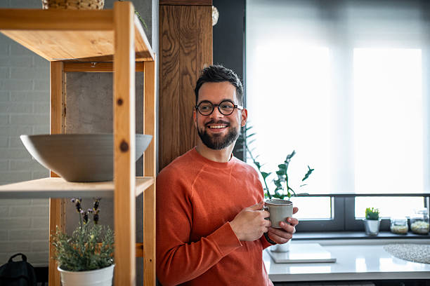 istock Young man smiling and holding a mug in his modern kitchen 2216032487