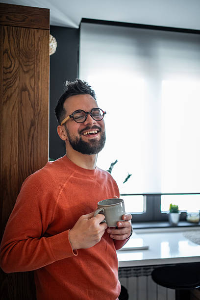 istock Happy young man laughing and drinking coffee in his modern kitchen 2216032502