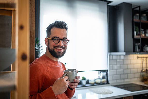 istock Young man smiling and holding a mug in his modern kitchen 2216032504