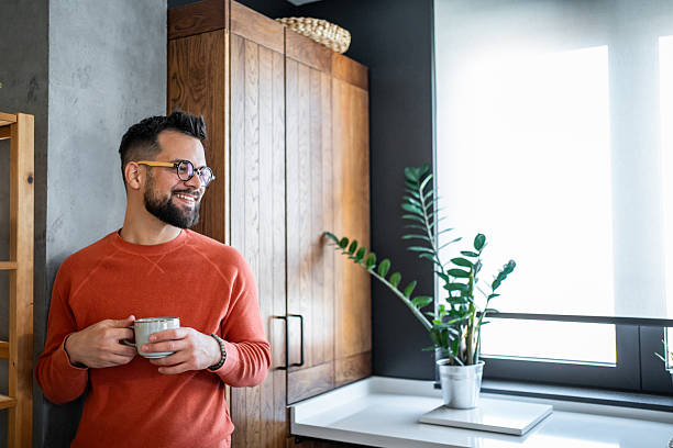 istock Young man smiling and drinking coffee in his modern kitchen 2216032516