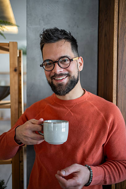 istock Young bearded man smiling and holding a mug in his modern apartment 2216032551