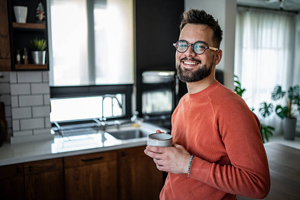 istock Young man smiling and drinking coffee in modern kitchen 2216032597
