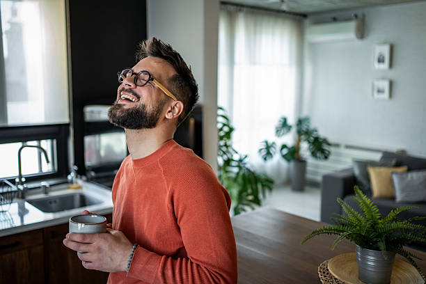istock Happy man laughing with coffee mug at home 2216032599