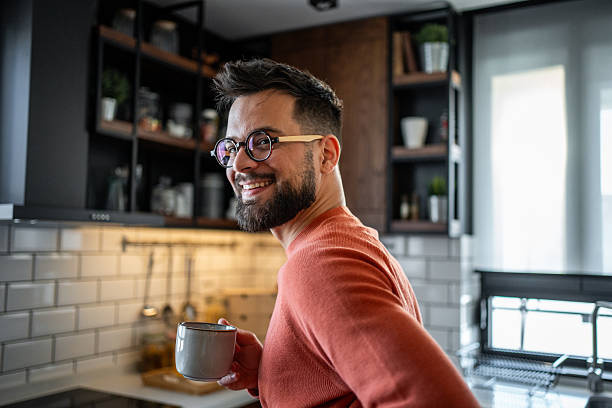 istock Smiling man holding coffee mug in modern kitchen 2216032600