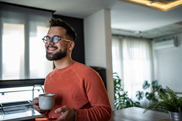 istock Young man enjoying morning coffee and using smartphone in kitchen 2216032613