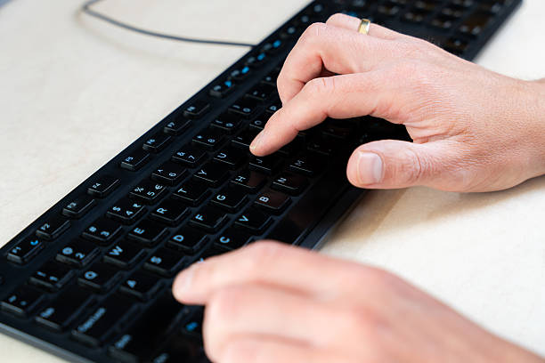 istock Top-down view of fingers pressing black keys on computer keyboard, workplace and technology context 2216035227