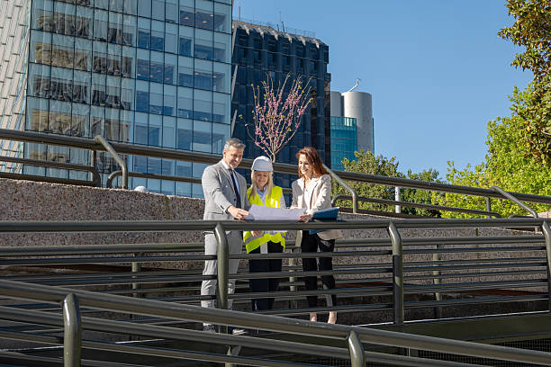 istock Professionals collaborating on a construction project, reviewing blueprints outdoors 2216035836