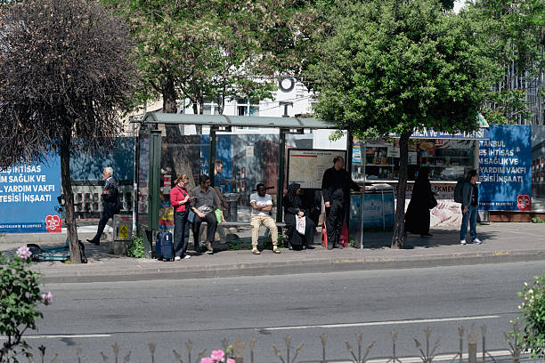 Istanbul, Turkey - May20 ,2025: Passengers gathered at a bus stop in Aksaray, one of Istanbul's vibrant neighborhoods. The scene depicts everyday urban life in Turkey, featuring locals waiting for their bus amidst trees and buildings, reflecting the city's dynamic pace and public transport infrastructure.