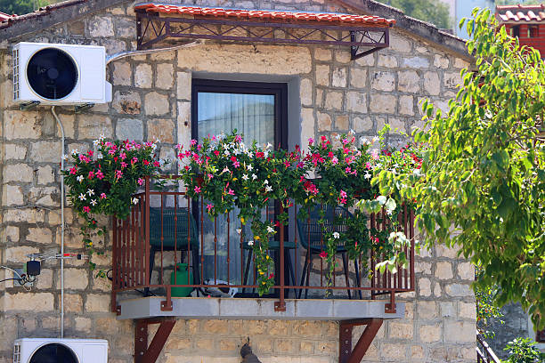 Balcony decorated with flower pots, cast iron railing, red geraniums. Stone house. Noia, A Coruña province, Galicia, Spain.