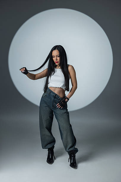 istock Young model in loose jeans and a crop top walking with confidence under studio lights. 2216044304
