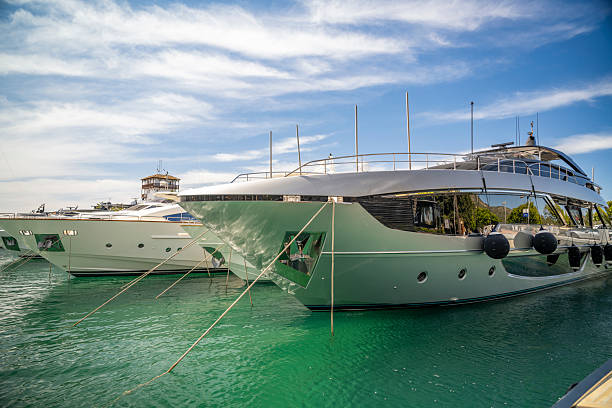 Sleek modern yachts are moored in the turquoise waters of a Majorca marina, set against a backdrop of blue skies and summer tranquility.