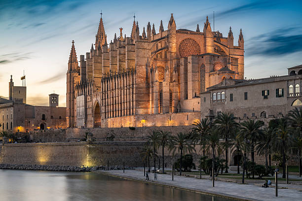 La Seu Cathedral glows in the warm evening light, its Gothic form reflected in the still waters of the Parc de la Mar.
