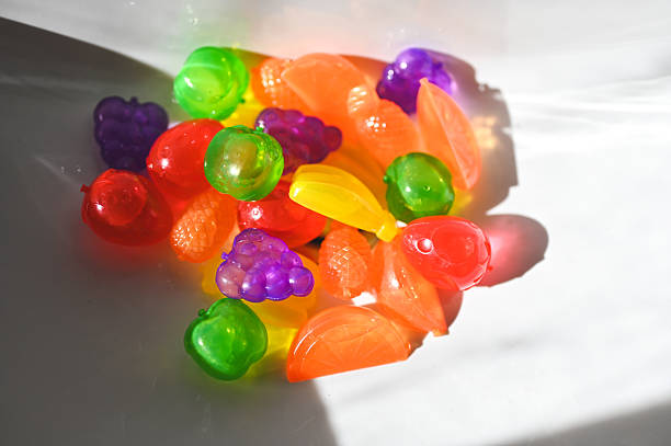 Colorful fruit-shaped ice cubes melting on white surface