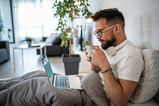 istock Young man working from home drinking a coffee in bed 2216051272