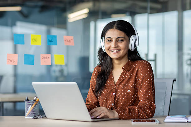 istock Young woman working inside office wearing headphones, programmer smiling and looking at camera, employee coding new software, developing applications 2216052140