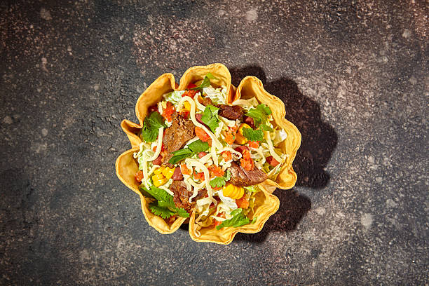 Taco salad in tortilla bowl with beef, cheese, corn and lettuce.