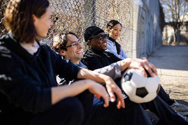 istock Diverse group relaxing along chain link fence with a soccer ball 2216058177