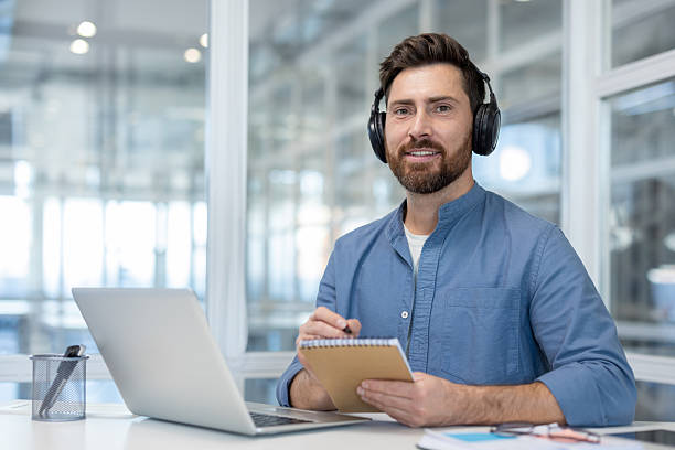 istock A man is seen watching a webinar and taking notes in a bright, modern office setting, with a laptop on the desk. 2216059463