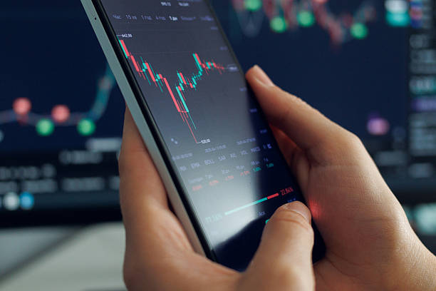 istock Person interacts with a smartphone showing stock market trends and data analysis, surrounded by additional financial graphics in the background 2216061955