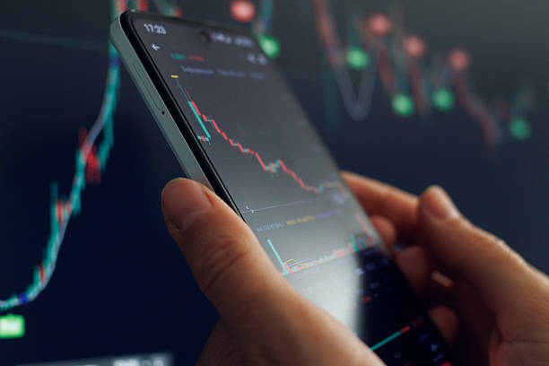 istock Trader utilizes smartphone to examine fluctuating stock market graphs and data trends during trading hours 2216061966