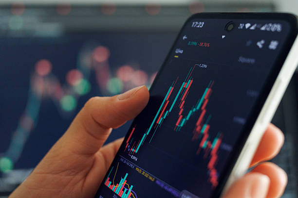 istock A person analyzes stock market data on a smartphone with colorful graphs displayed, set against a financial trading background 2216061969