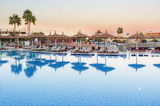 istock Resort pool surrounded by sunbeds and palm trees during sunset in a tropical location 2216064556