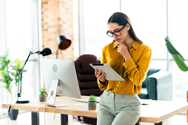 istock Young professional businesswoman using a digital tablet while working in a modern office featuring stylish interiors and natural lighting 2216065906