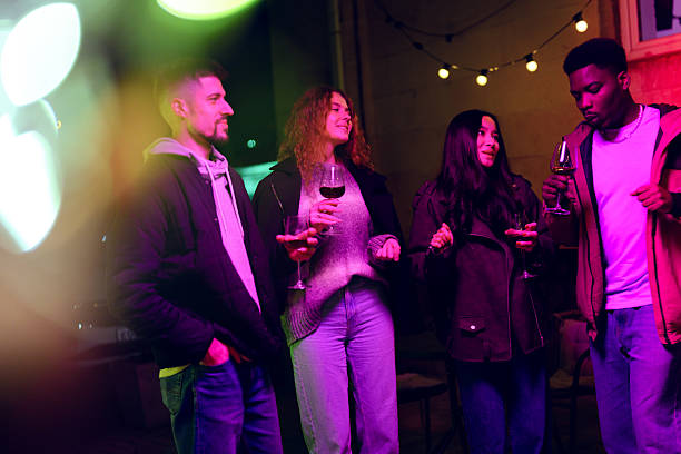 istock Group of friends enjoying a lively evening outdoors with drinks under string lights in a vibrant setting 2216066143
