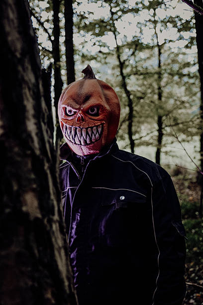 istock Person in Pumpkin Mask Standing in Forest 2216067174