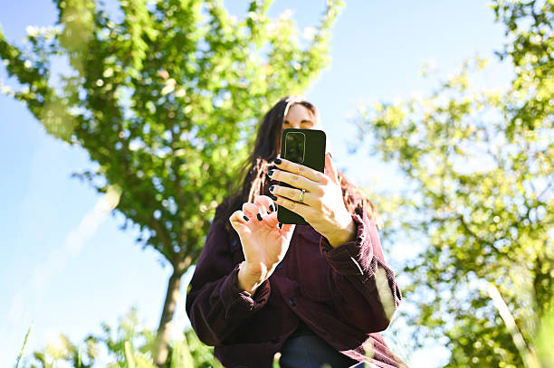 istock Young woman using smartphone in a park on a sunny day 2216070417