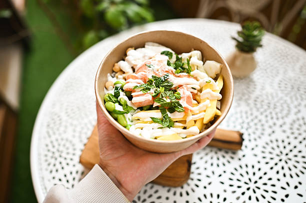 istock Customer holding a delicious poke bowl with salmon, mango and edamame 2216071368