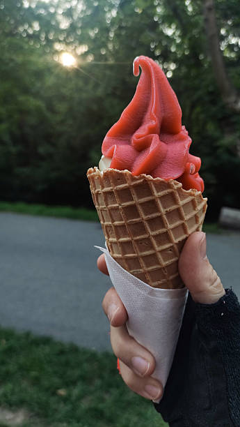 istock Cyclist holding red fruit strawberry ice cream in waffle cone during sunset 2216076041