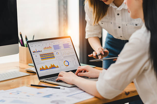 istock Two women working together on data analysis using laptop with colorful charts and graphs on screen, discussing business strategy in modern office environment 2216076326