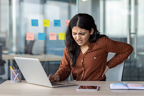 istock A young woman suffering from back pain while working on a laptop in the office. 2216076540