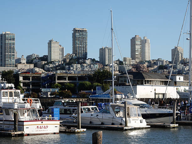 San Francisco, California, USA- July 5, 2024: Boats moored at San Francisco's Fisherman's Wharf, with the city skyline behind.