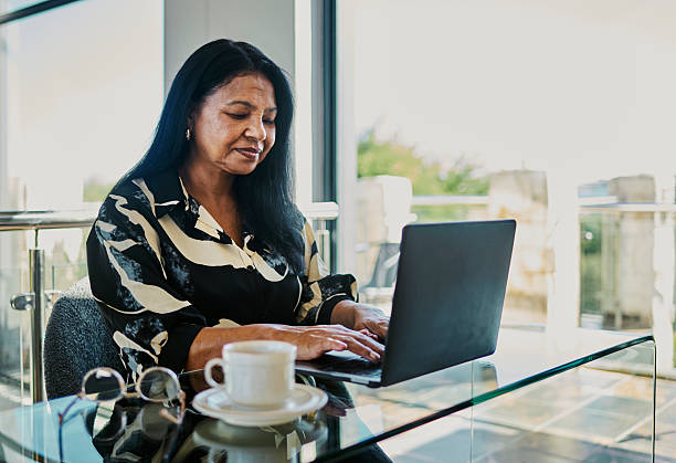 istock Focused Mature Woman Typing on Laptop with Coffee 2216078521