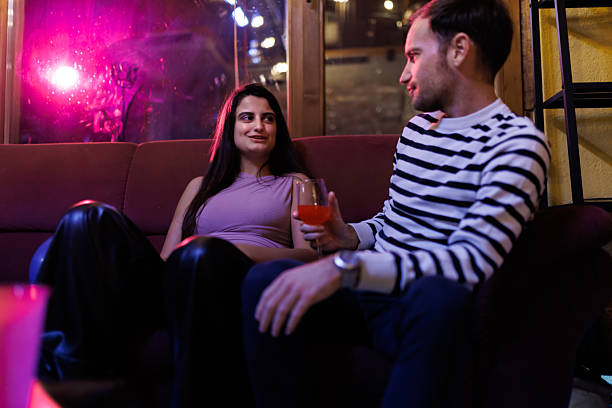 istock Casual Conversation Between Two Friends Relaxing on a Couch with Drinks in a Vibrant Interior 2216079598