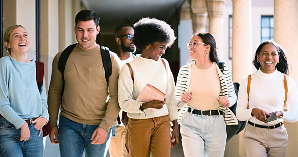 istock Group of Diverse Students Laughing And Talking While Walking in a Bright College Hallway 2216080499
