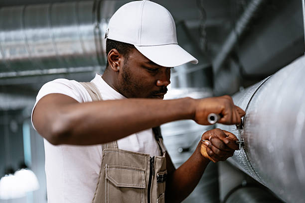 istock Skilled worker repairs industrial piping in a modern facility during daylight hours while using a wrench for adjustment 2216080792