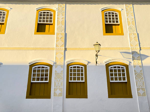Colorful colonial buildings in Paraty showcase unique architectural details with yellow accents. The sun casts soft shadows, enhancing the beauty of this touristic destination in Brazil.