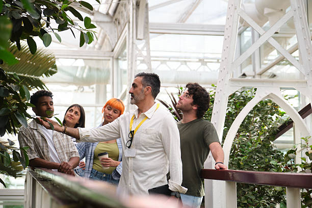 istock Tour guide explaining exotic plants to students in botanical garden 2216085198