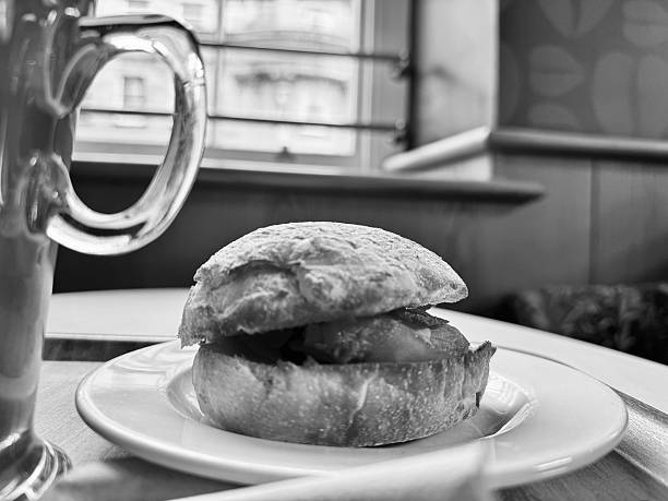 A bacon sandwich on a plate on a cafe table
