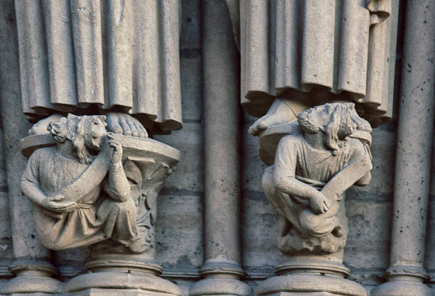 Notre Dame de Paris Cathedral Gothic style. Architectural details. Virtues trampling on vices, ordinary mortals, volute in startled figures of people, pedestal